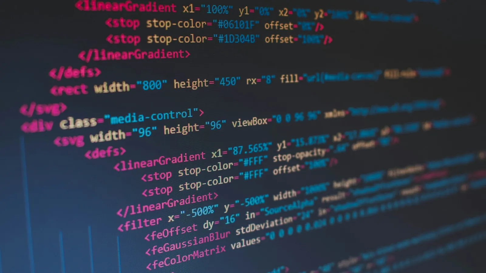 Színes HTML- és SVG-kódsorok sötét kódszerkesztőben, közelről fotózva.